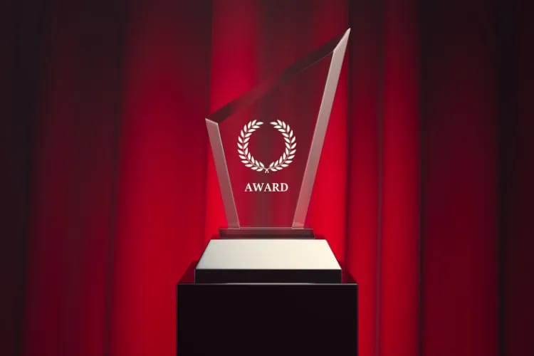 A beautifully engraved crystal award on a display stand, catching stage light with a premium sparkle.