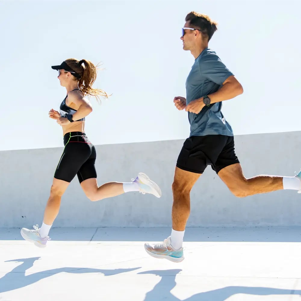 Two runners mid-stride on a sunlit rooftop track