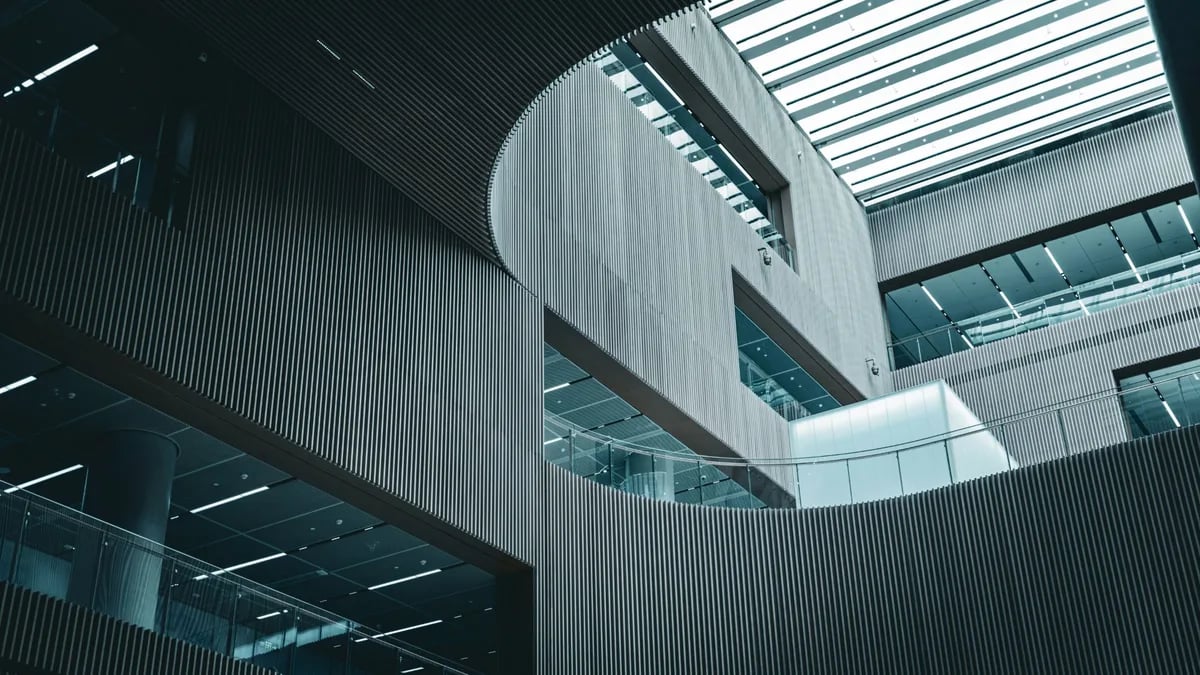 The atrium of a modern convention centre, curved timber-slatted walls under a glass roof