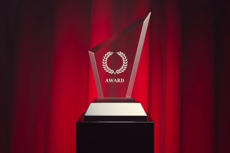 A beautifully engraved crystal award on a display stand, catching stage light with a premium sparkle.