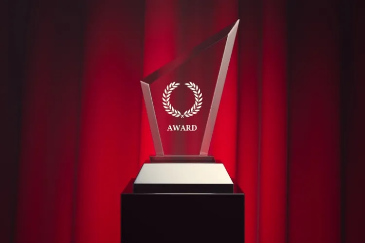 A beautifully engraved crystal award on a display stand, catching stage light with a premium sparkle.