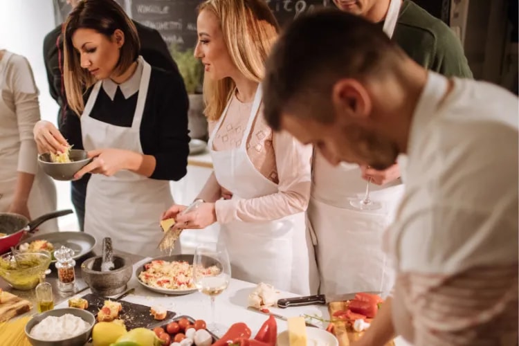 A chef leading a hands-on cooking class for guests inside a restaurant kitchen.